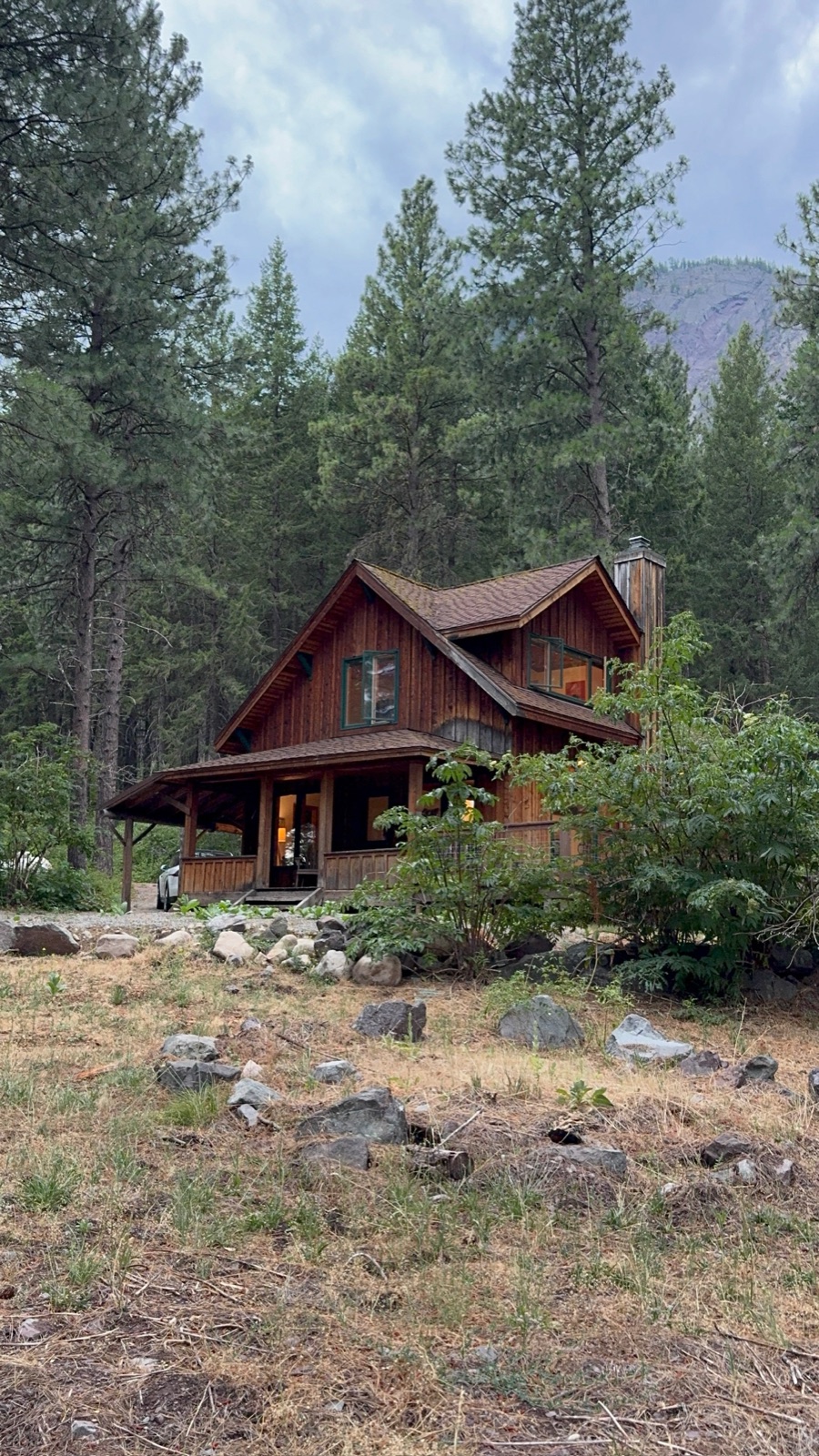 The Dog Cabin nestled among ponderosa pines, with its covered front porch and warm interior light
