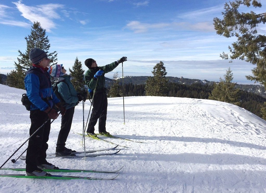 Cross-country skiers on a snowy ridge with mountain views